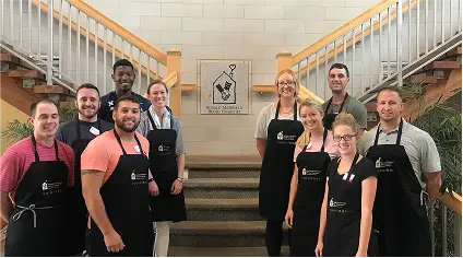 Group of Horizon Community Fund participants wearing aprons and posing on a staircase.