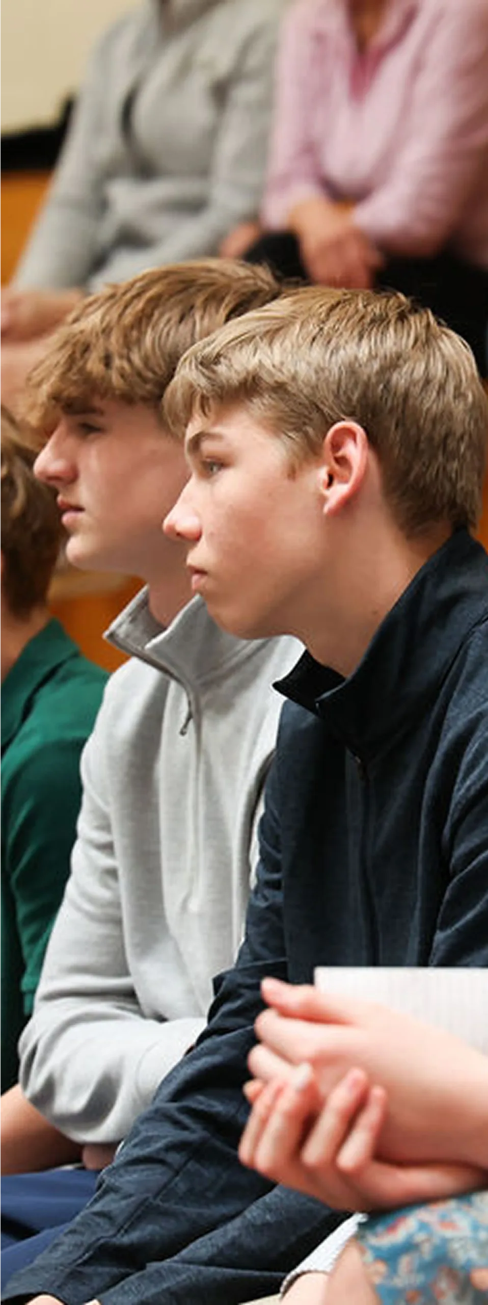 Two students attentively watching a presentation in a classroom or assembly.